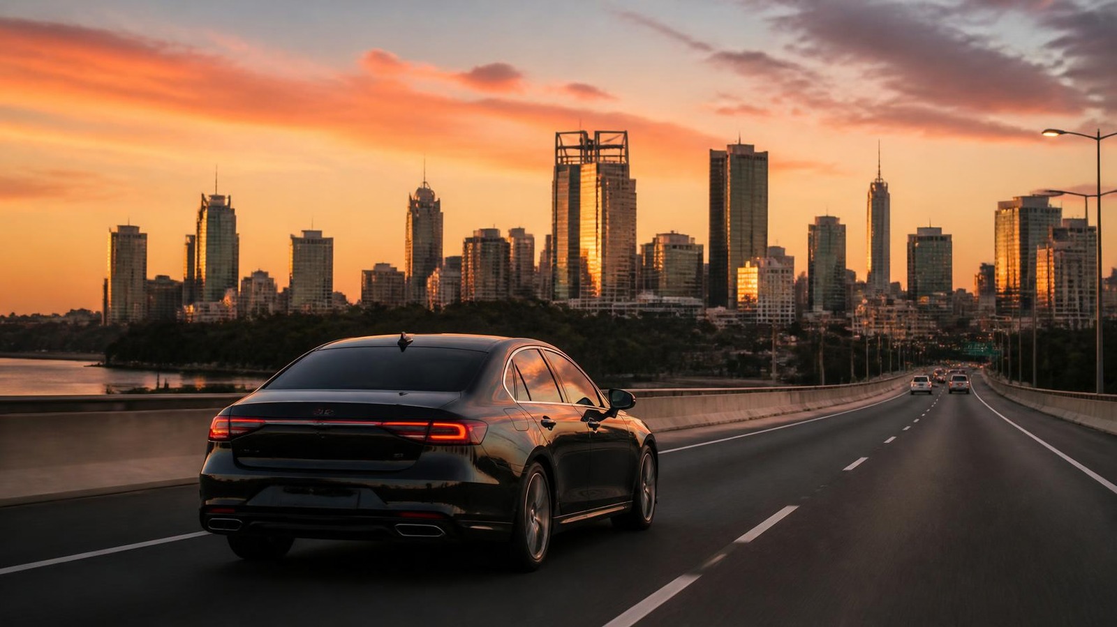 Black sedan driving toward an Australian city at sunset