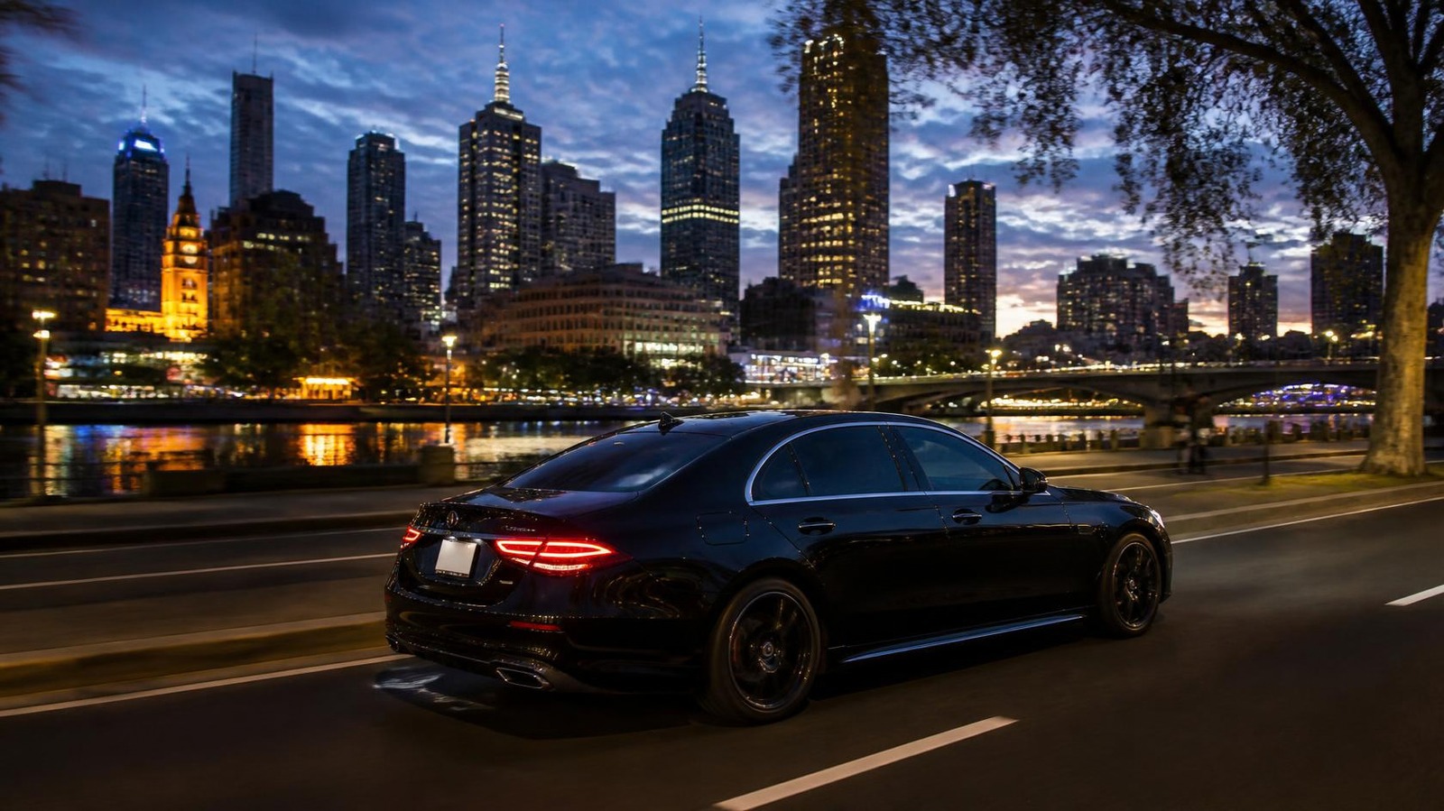Black sedan driving through Melbourne at dusk